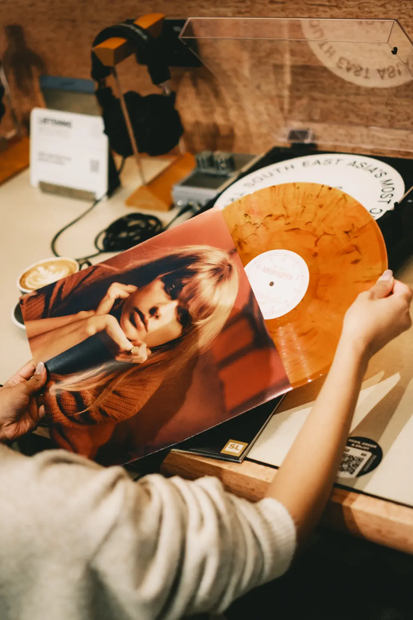 A hand holding a record over a turntable